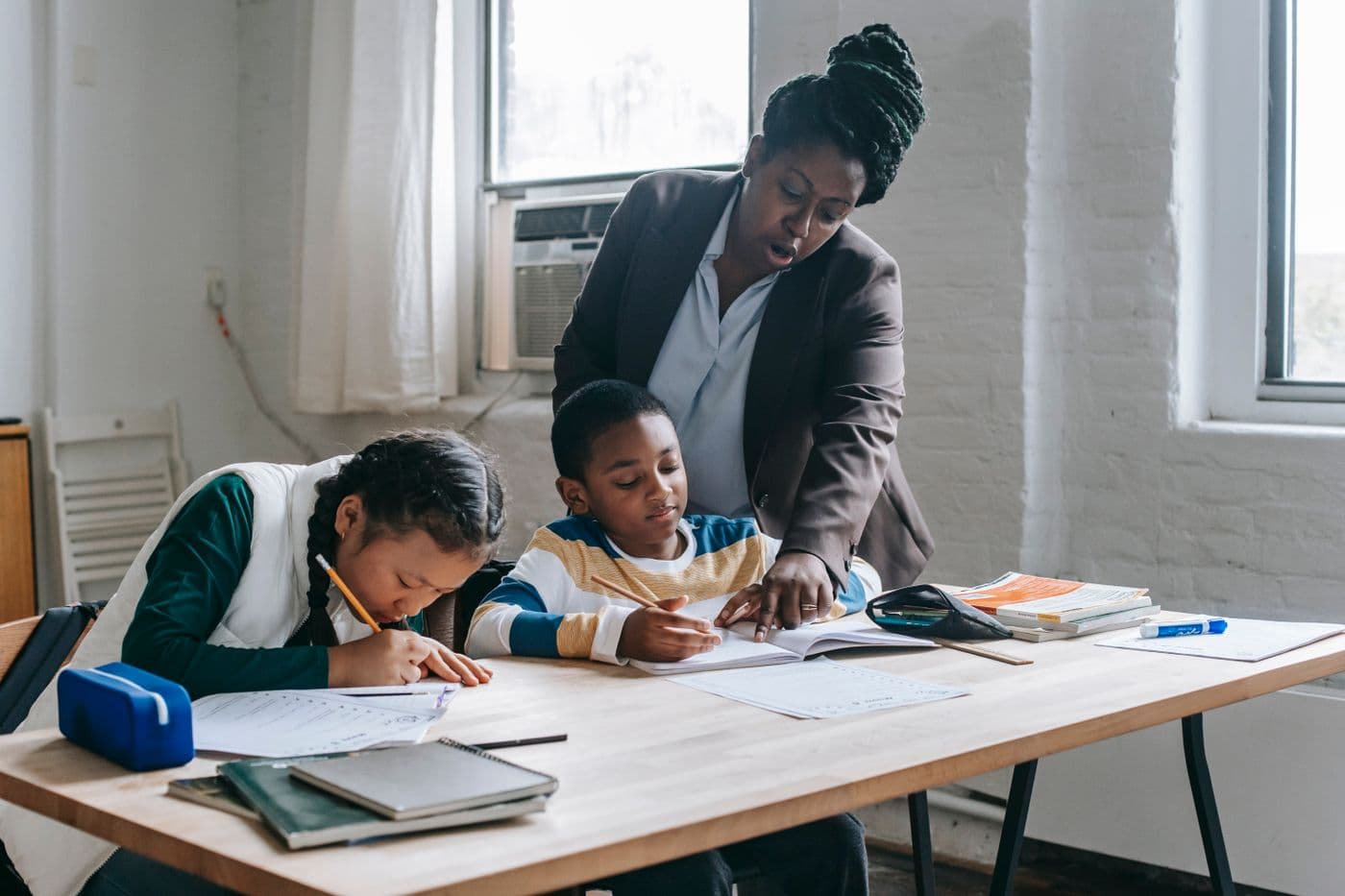 A teacher helping two pupils with their work at a desk